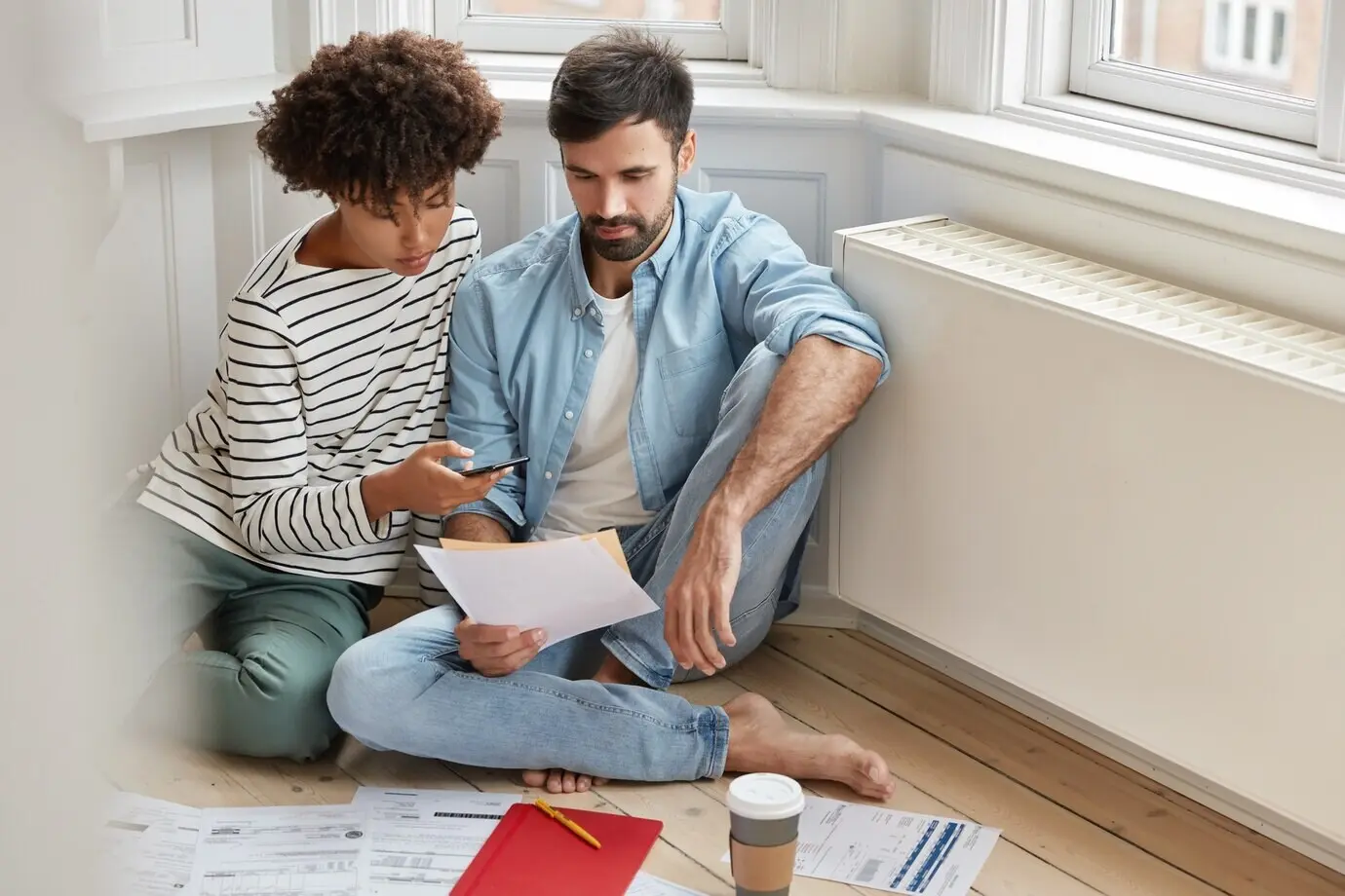 Eine unbeschwerte Frau und ein Mann unterschiedlicher ethnischer Herkunft prüfen Unterlagen.